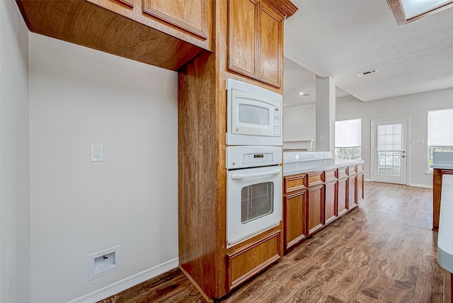 kitchen featuring hardwood / wood-style floors, white appliances, and a textured ceiling