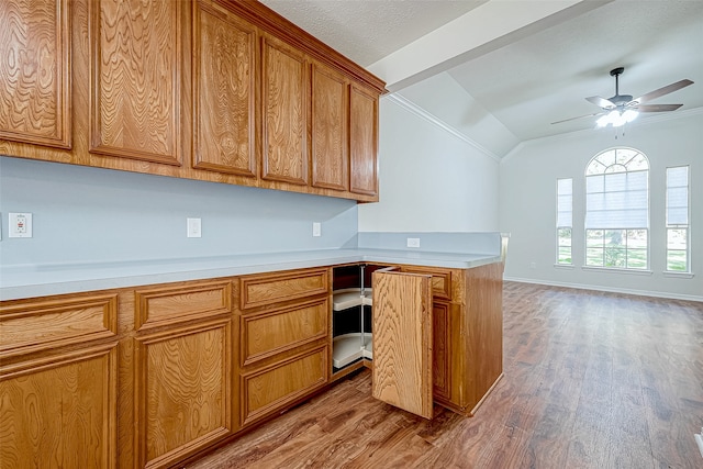 kitchen featuring ceiling fan, crown molding, wood-type flooring, built in desk, and lofted ceiling