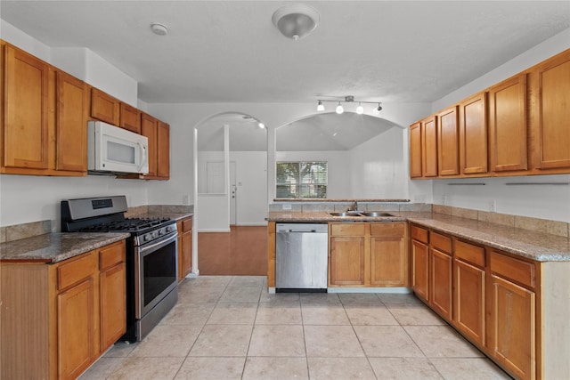 kitchen with stone counters, sink, light tile patterned floors, and appliances with stainless steel finishes