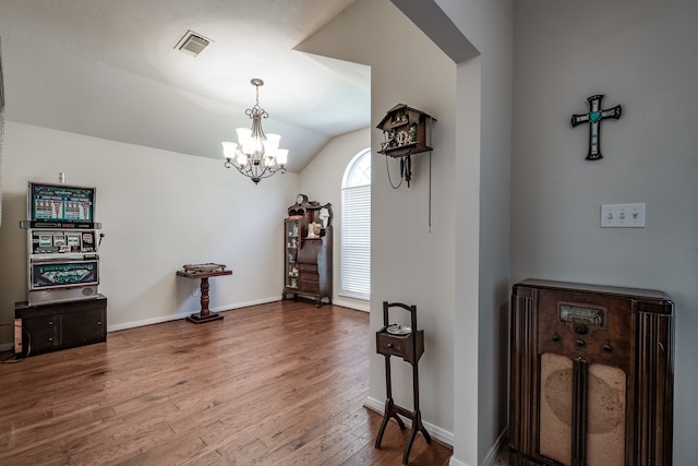 foyer entrance with hardwood / wood-style flooring, lofted ceiling, and an inviting chandelier