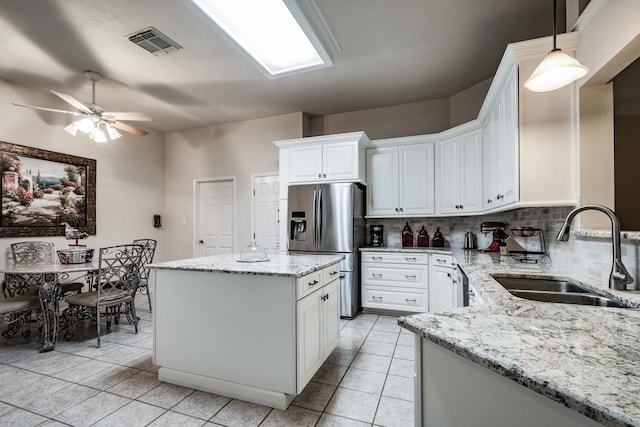 kitchen featuring sink, stainless steel refrigerator with ice dispenser, backsplash, decorative light fixtures, and white cabinets