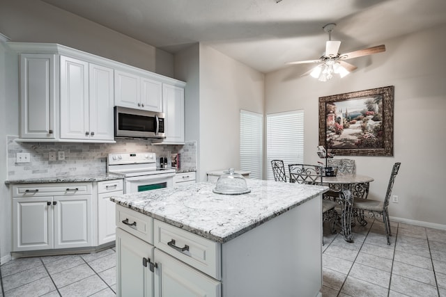 kitchen with backsplash, white cabinets, white electric range, ceiling fan, and a kitchen island