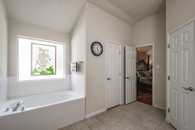 bathroom with tile patterned flooring, a healthy amount of sunlight, a tub, and vaulted ceiling