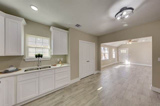 kitchen featuring white cabinets, light hardwood / wood-style floors, sink, and a wealth of natural light