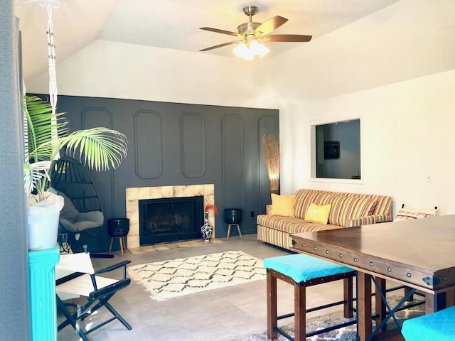 living room with ceiling fan, lofted ceiling, and a fireplace