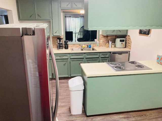 kitchen featuring sink, green cabinets, light hardwood / wood-style flooring, and appliances with stainless steel finishes