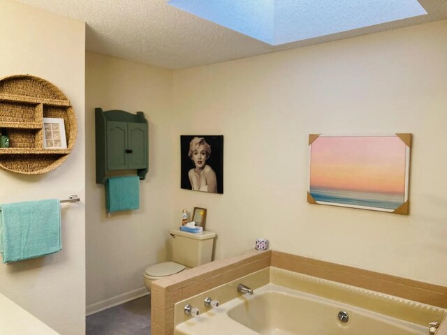 bathroom featuring a tub to relax in, a skylight, toilet, and a textured ceiling