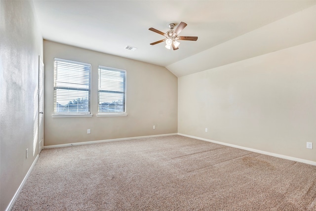 spare room featuring light colored carpet, vaulted ceiling, and ceiling fan