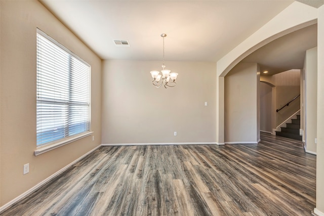 unfurnished room featuring dark hardwood / wood-style flooring, a wealth of natural light, and a notable chandelier