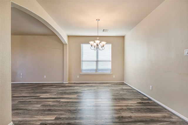 spare room featuring dark hardwood / wood-style flooring and an inviting chandelier