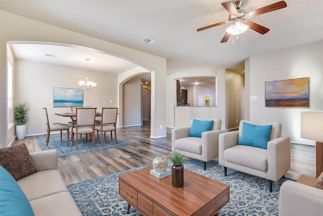 living room with wood-type flooring and ceiling fan with notable chandelier