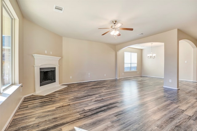 unfurnished living room with ceiling fan with notable chandelier and dark hardwood / wood-style flooring