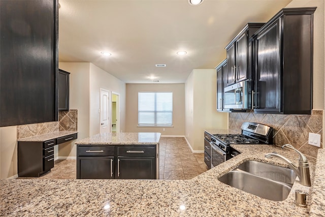 kitchen with backsplash, light stone counters, sink, and stainless steel appliances