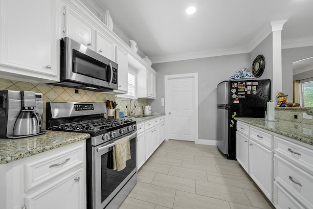 kitchen with light stone counters, sink, white cabinets, and appliances with stainless steel finishes