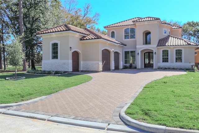 mediterranean / spanish house with french doors, a garage, and a front lawn