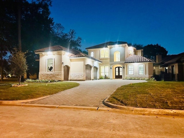 mediterranean / spanish house with a lawn, a garage, and french doors