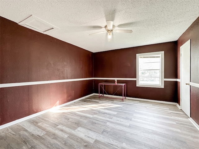 empty room with a textured ceiling, light hardwood / wood-style floors, and ceiling fan