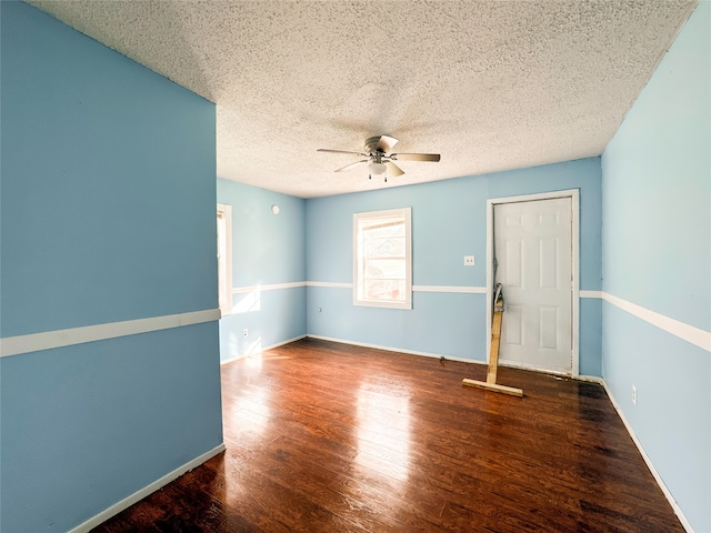 empty room with a textured ceiling, dark hardwood / wood-style flooring, and ceiling fan