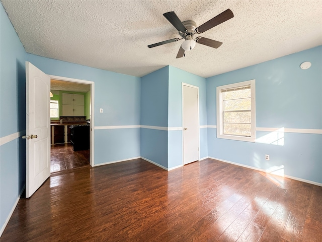 empty room with a textured ceiling, dark hardwood / wood-style floors, and ceiling fan