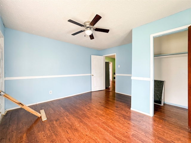 unfurnished bedroom with ceiling fan, dark hardwood / wood-style flooring, and a textured ceiling