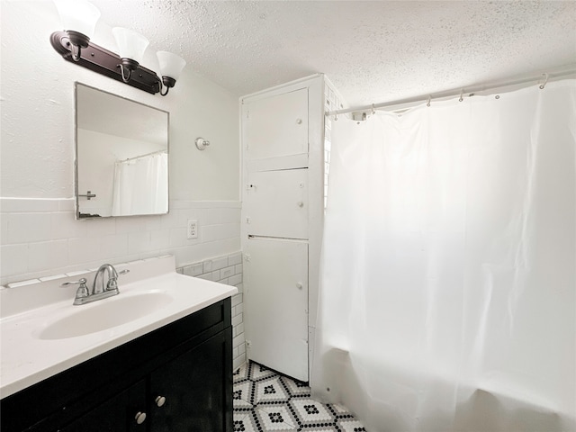 bathroom with vanity, a textured ceiling, tile walls, and shower / bath combo with shower curtain