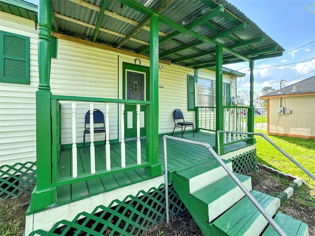 view of exterior entry with covered porch and a deck