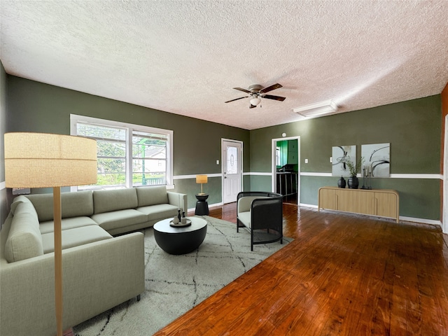 living room with ceiling fan, wood-type flooring, and a textured ceiling