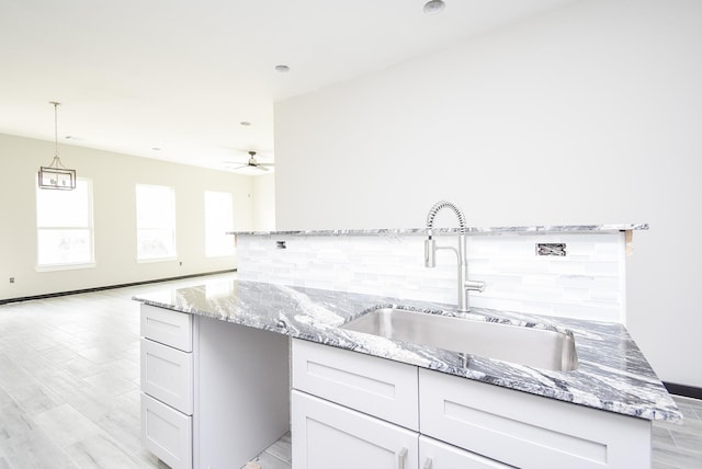 209 Silverleaf Rd, Sweeny, TX 77480 - kitchen featuring a sink, backsplash, light stone countertops, and a ceiling fan