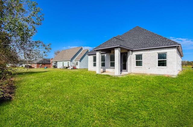 209 Silverleaf Rd, Sweeny, TX 77480 - rear view of property featuring a shingled roof, brick siding, and a yard