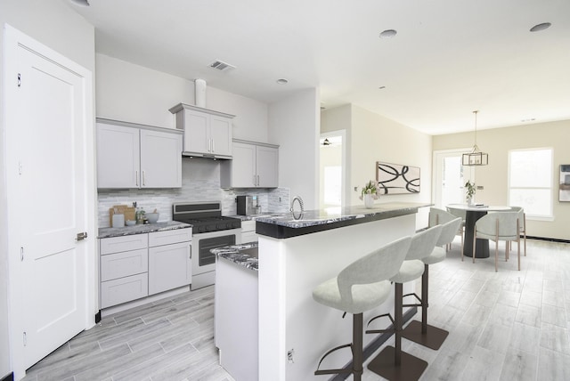 209 Silverleaf Rd, Sweeny, TX 77480 - kitchen with gas range, tasteful backsplash, gray cabinets, a breakfast bar area, and an island with sink