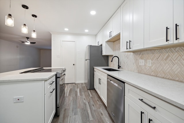 kitchen with light stone countertops, appliances with stainless steel finishes, sink, light hardwood / wood-style floors, and white cabinetry