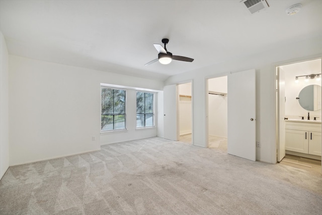 unfurnished bedroom featuring connected bathroom, light colored carpet, and ceiling fan