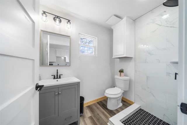 bathroom with a tile shower, toilet, vanity, and hardwood / wood-style flooring