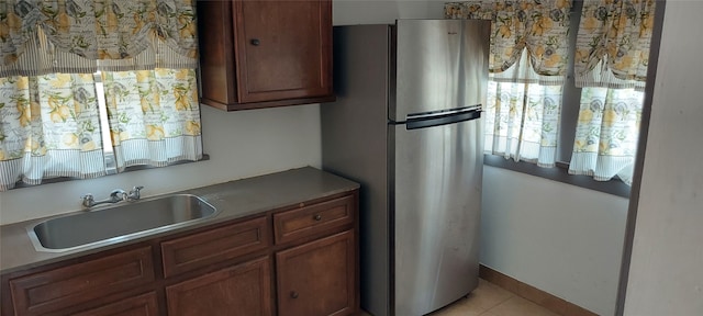 kitchen with stainless steel fridge, light tile patterned floors, and sink