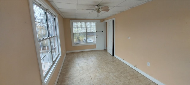 spare room with a paneled ceiling, ceiling fan, and a healthy amount of sunlight