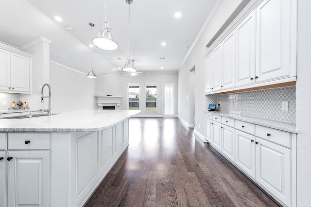 kitchen featuring backsplash, ornamental molding, dark wood-type flooring, decorative light fixtures, and white cabinetry