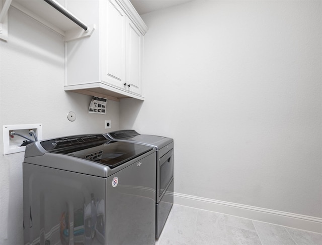 clothes washing area with washer and clothes dryer, light tile patterned floors, and cabinets