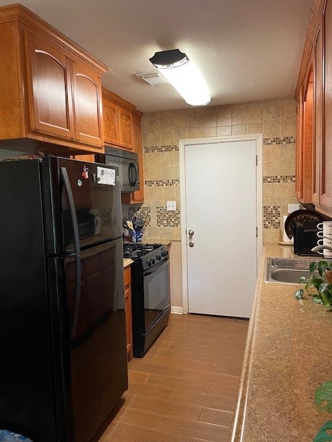 kitchen featuring sink, light hardwood / wood-style flooring, and black appliances