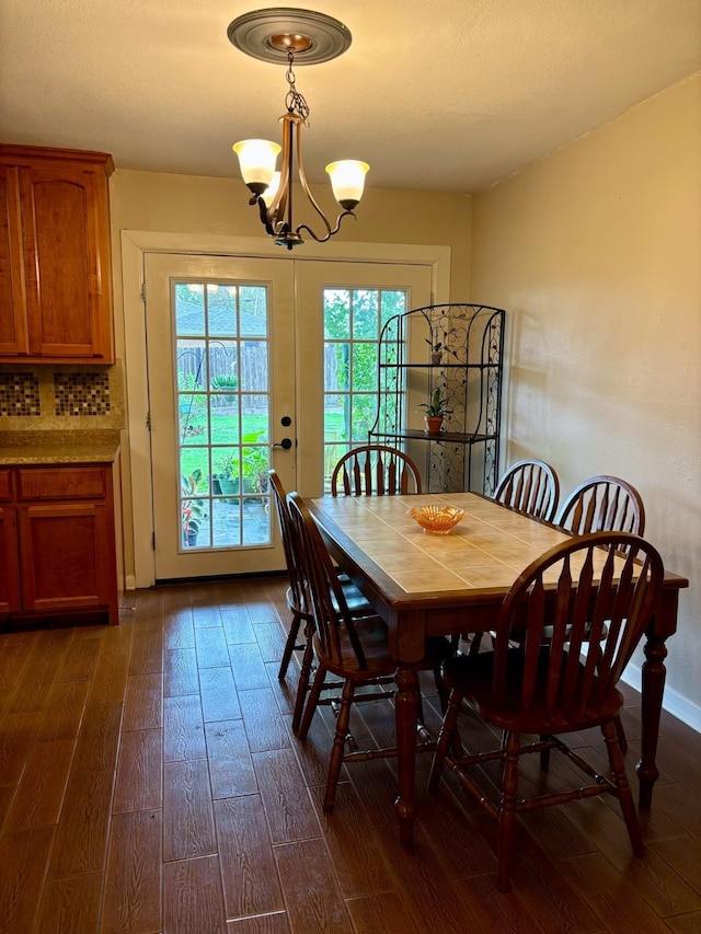 dining space with french doors, dark wood-type flooring, and a chandelier