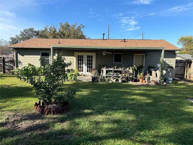 rear view of property featuring a lawn, ceiling fan, and french doors