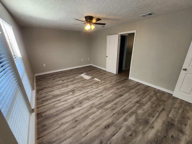 unfurnished bedroom with ceiling fan, dark hardwood / wood-style floors, and a textured ceiling