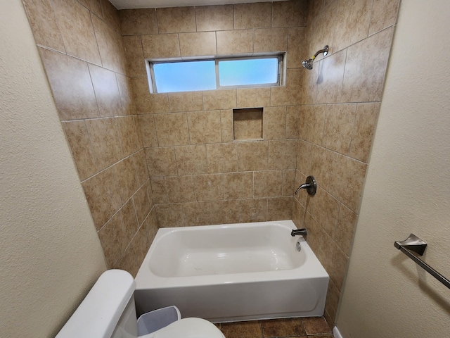 bathroom featuring toilet and tiled shower / bath