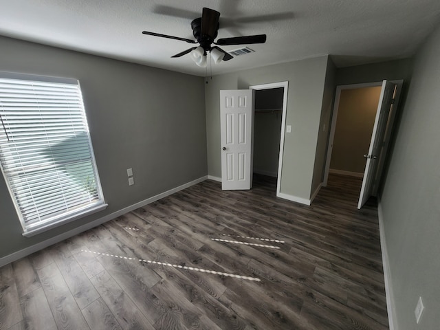 unfurnished bedroom featuring multiple windows, a walk in closet, a closet, and ceiling fan