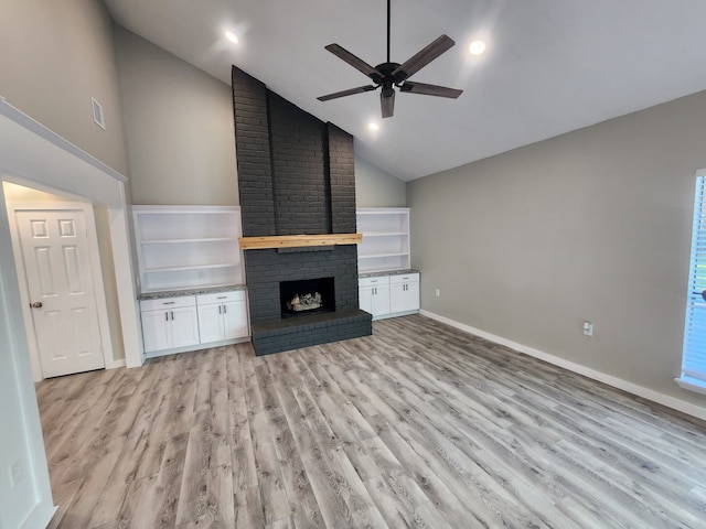 unfurnished living room featuring ceiling fan, high vaulted ceiling, light wood-type flooring, and a brick fireplace