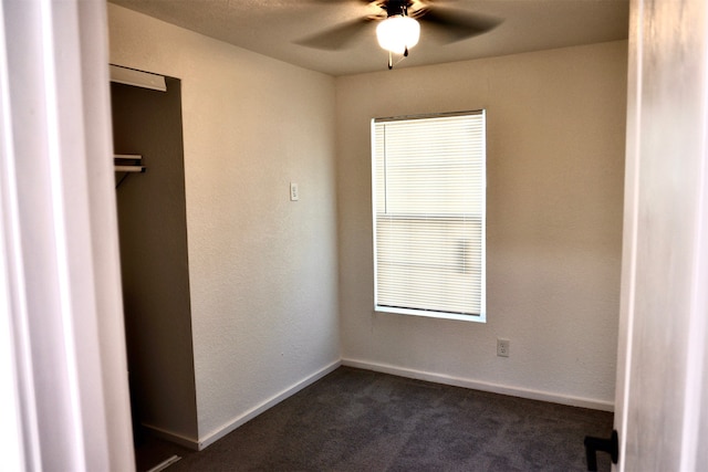 unfurnished bedroom with ceiling fan and dark colored carpet