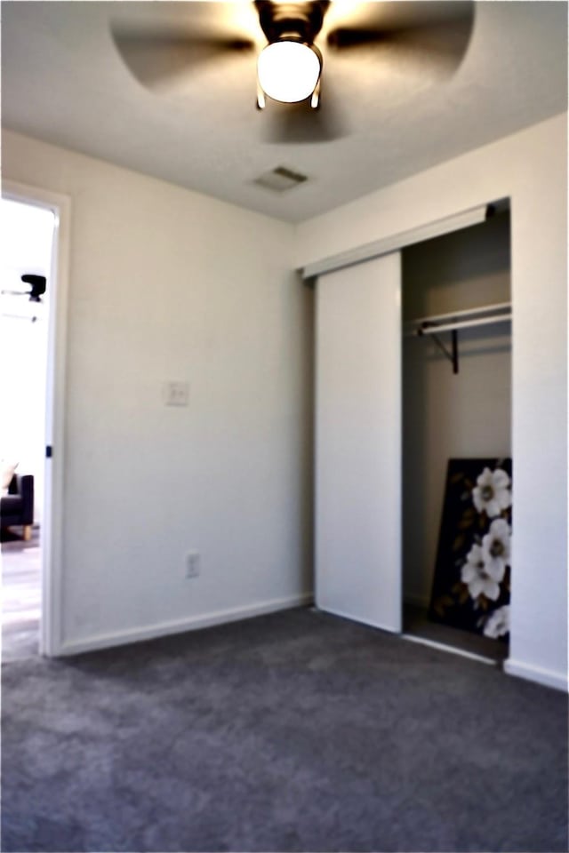 unfurnished bedroom with ceiling fan, a closet, and dark colored carpet