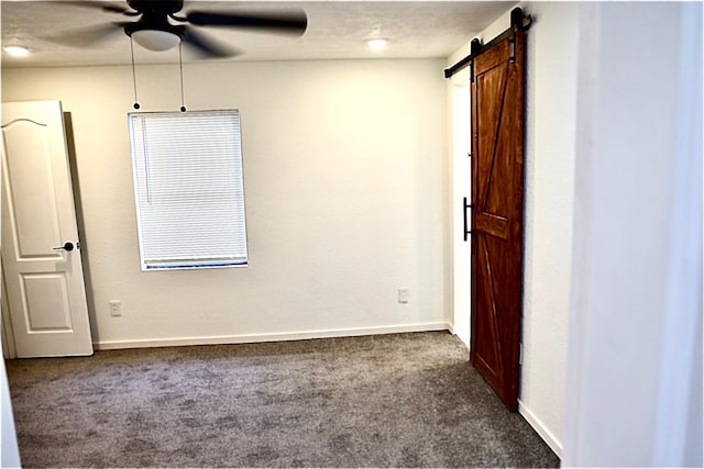 carpeted spare room featuring a barn door, ceiling fan, and a textured ceiling