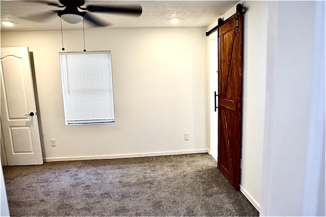 spare room with a barn door, carpet floors, a textured ceiling, and ceiling fan