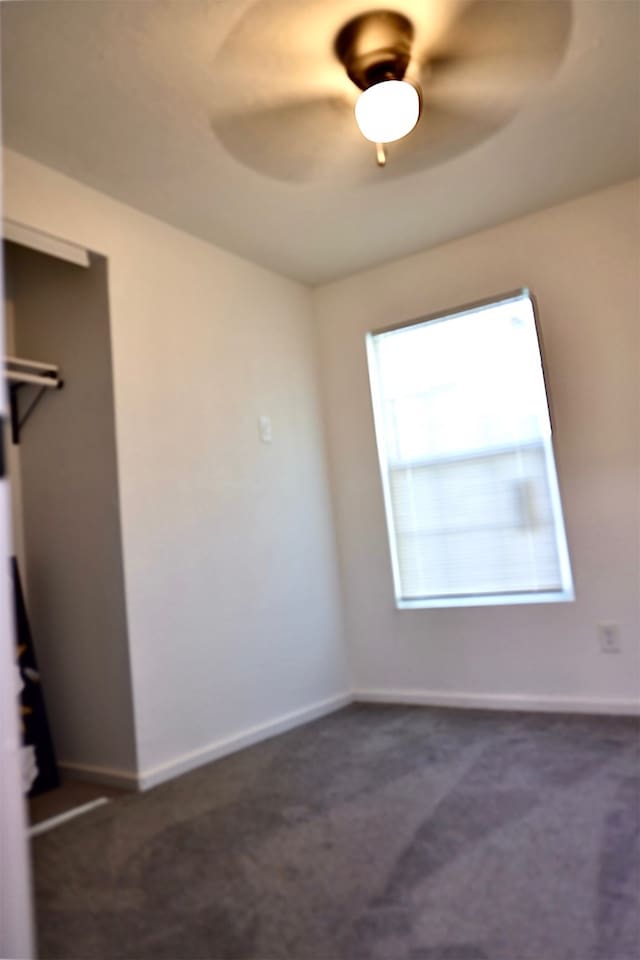 empty room with dark colored carpet and ceiling fan