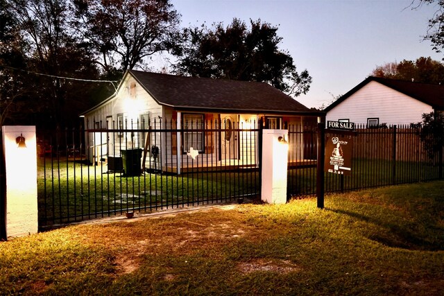 back house at dusk featuring a lawn